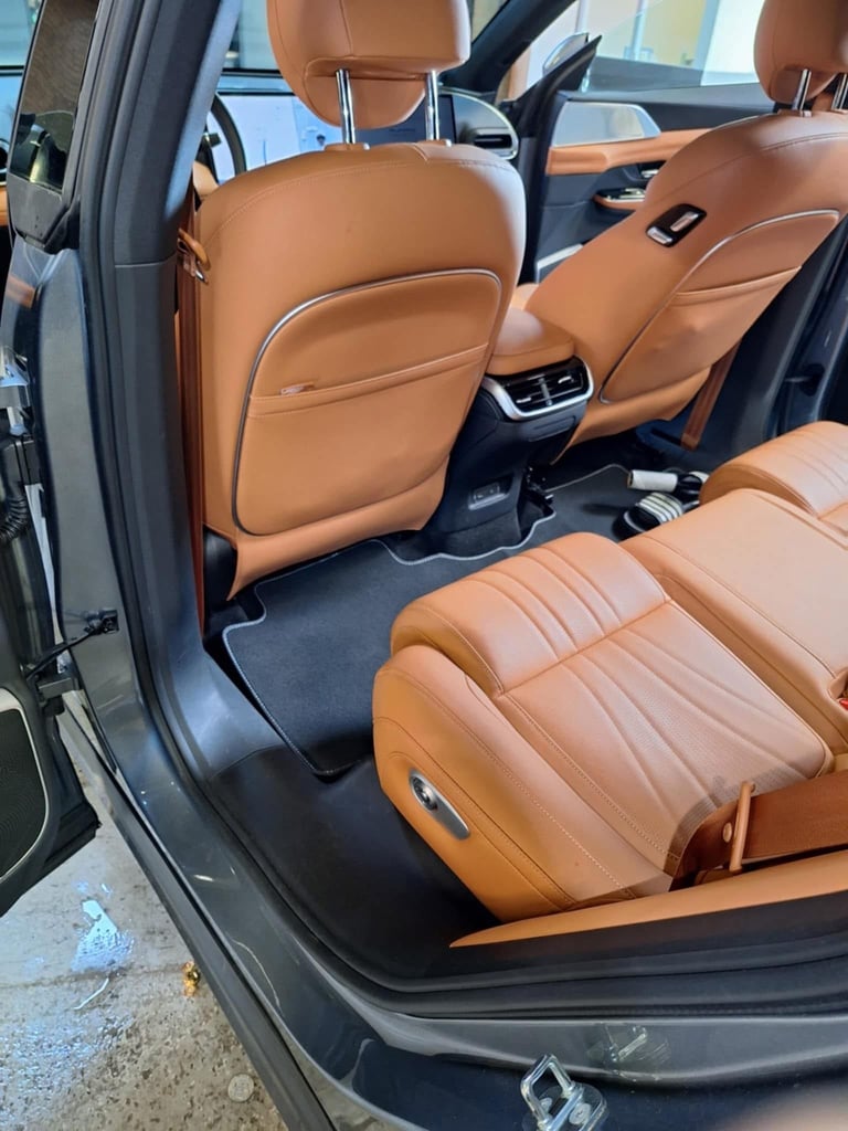 Interior view of car with brown leather seats, open drivers door, and air vents visible on back of front seats